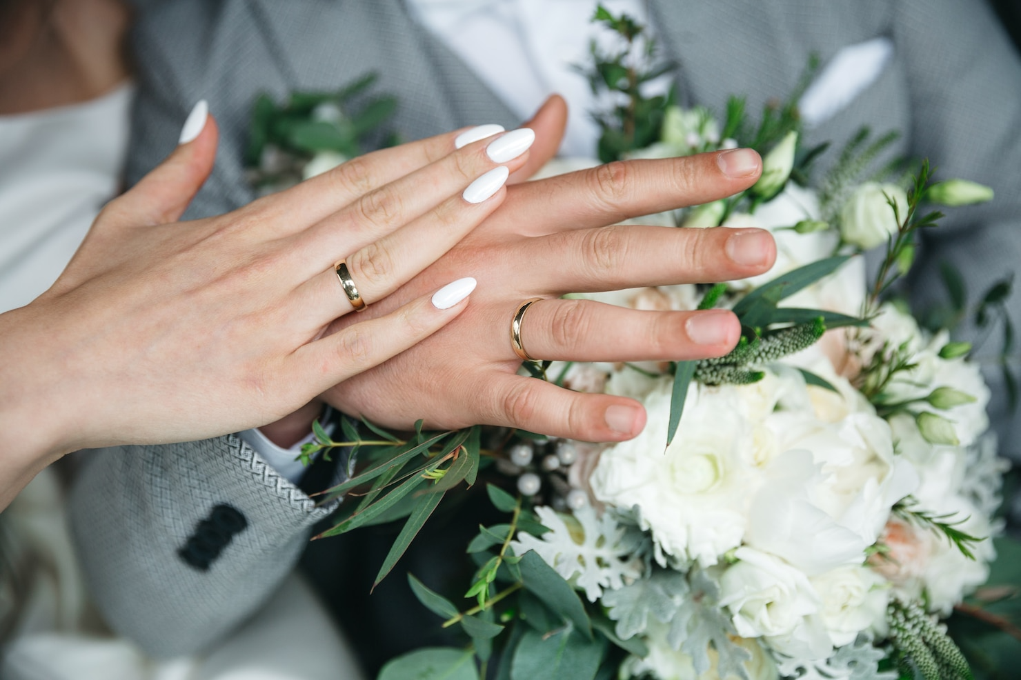A close up of a bride and groom 's hands with wedding rings.