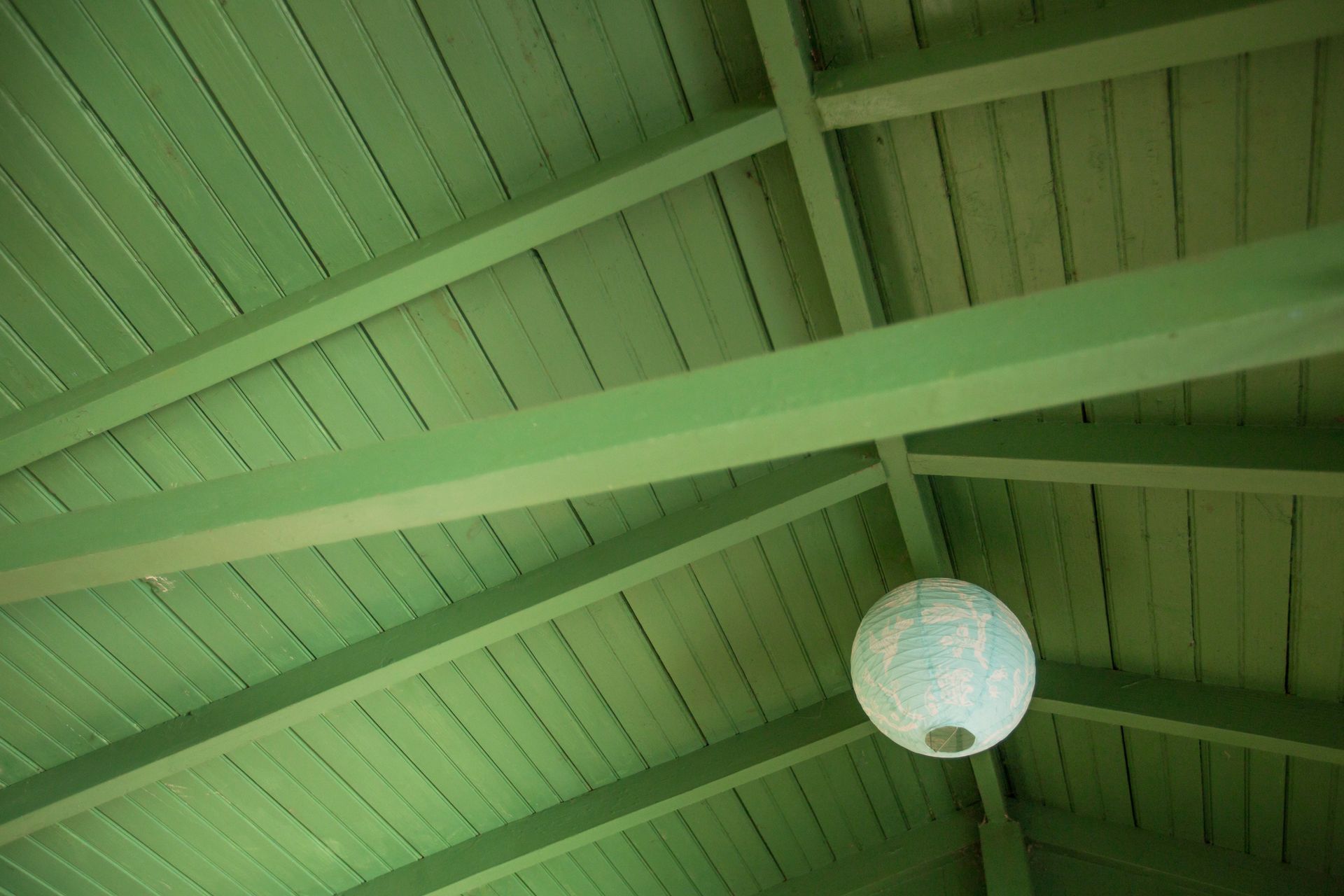 A green ceiling with a white lantern hanging from it.