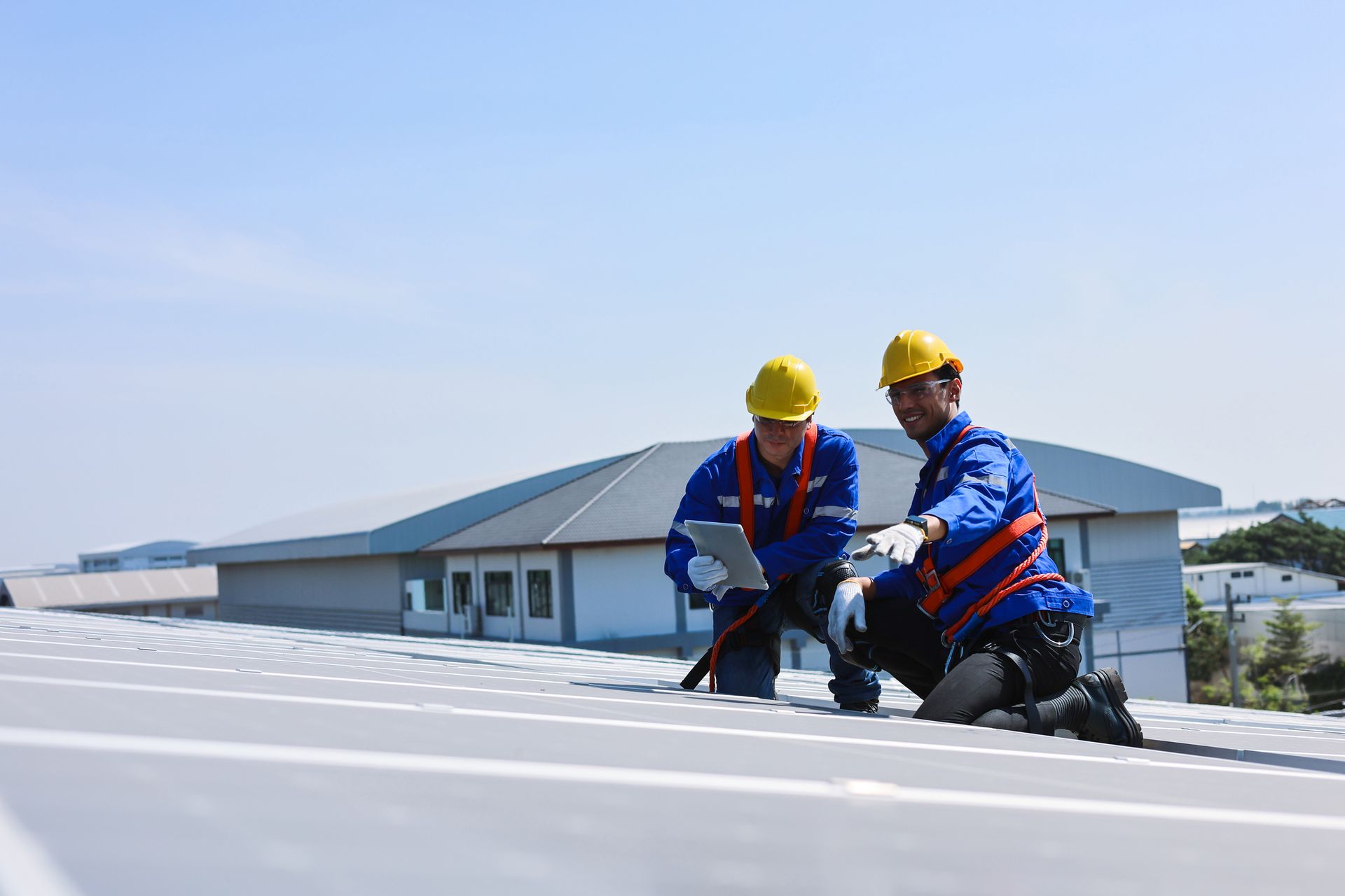 Two construction workers are working on the roof of a building.