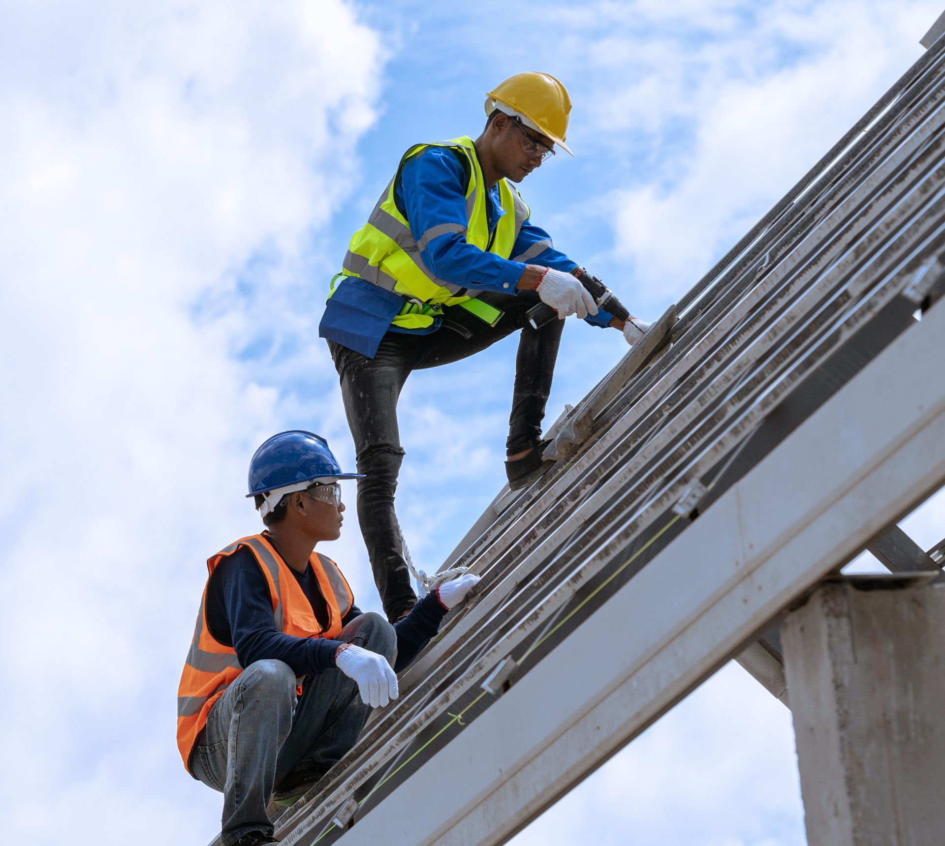 Two construction workers are working on the roof of a building.