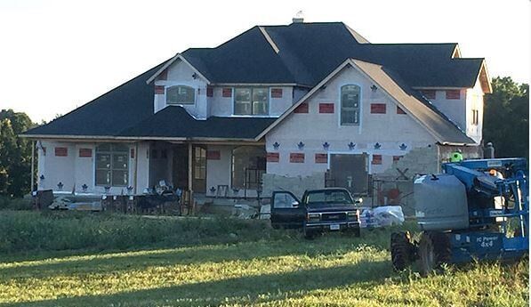 A large house is being built in a grassy field.