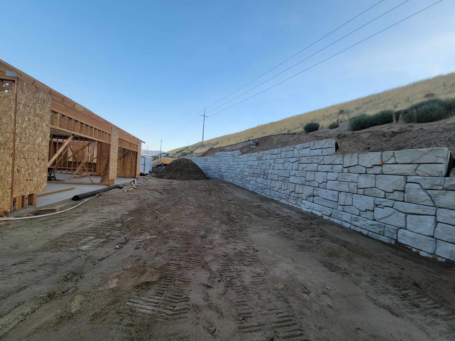 Construction site with a stone retaining wall and a partially built wooden structure.