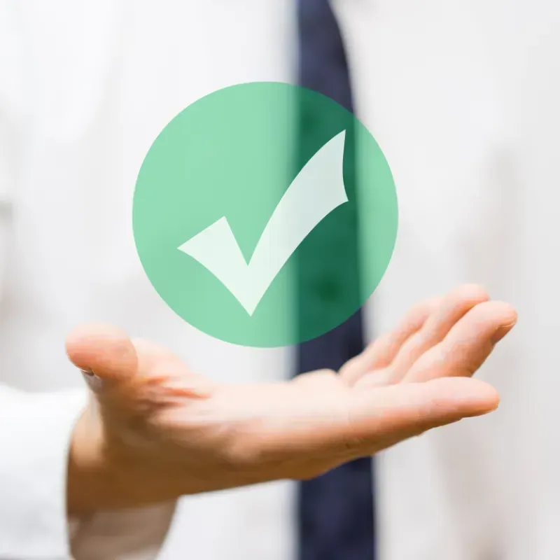A person is holding a green check mark in their hand