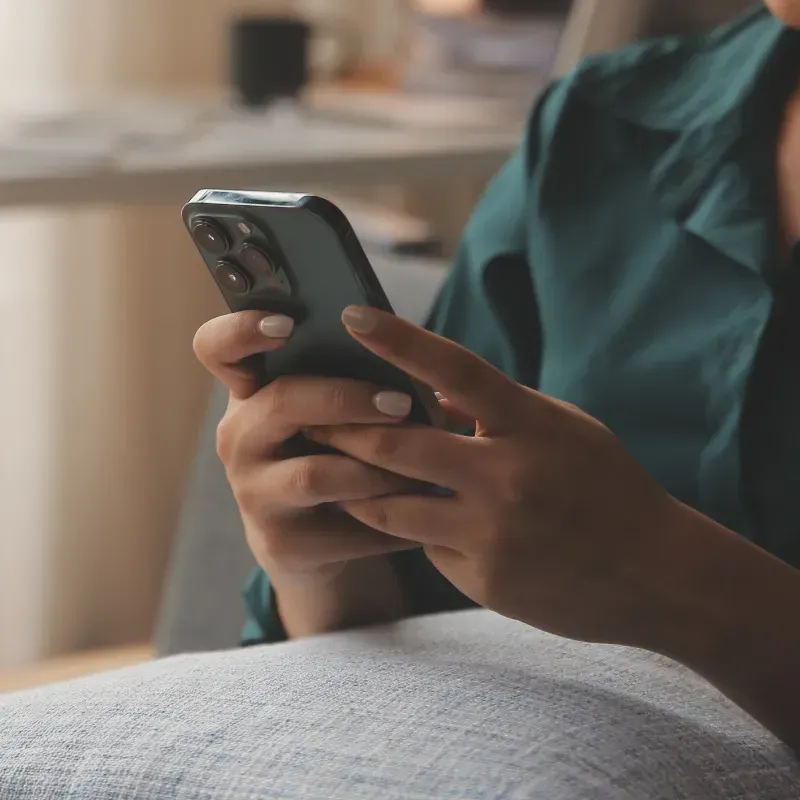 A woman is sitting on a couch using a mobile phone.