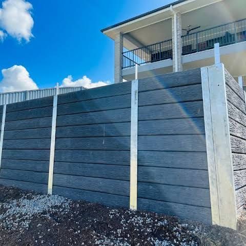 A fence is being built in front of a house with a balcony.