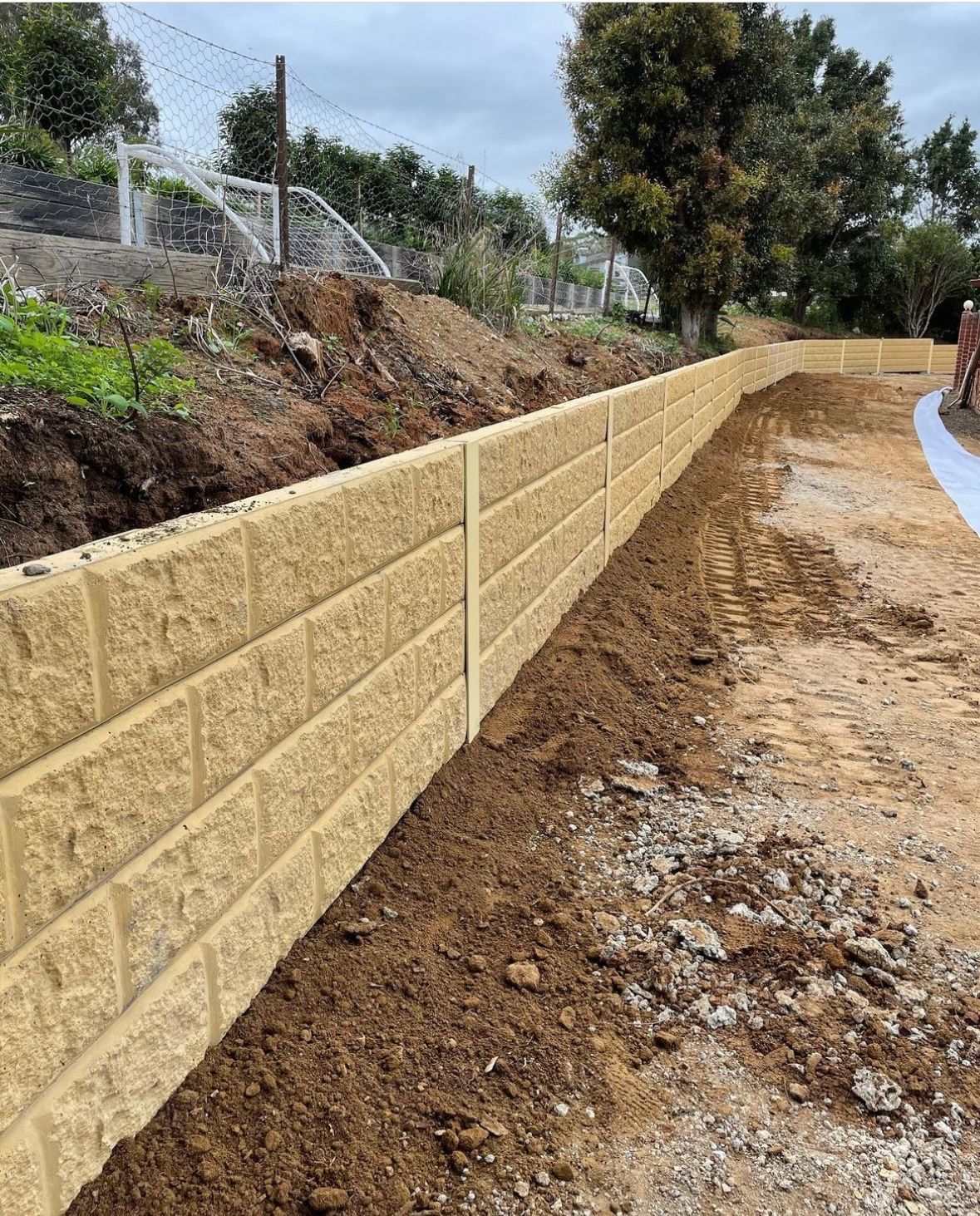 A brick wall is being built on top of a dirt hill.