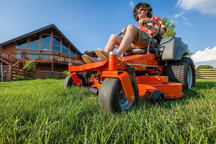 man wearing hat and sunglasses using a riding lawnmower