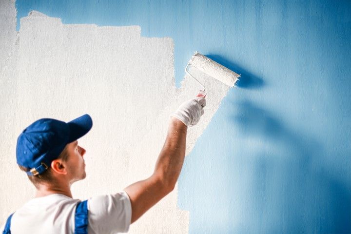 A picture of a man in a blue hat painting the interior of a house in Puyallup, Washington. 