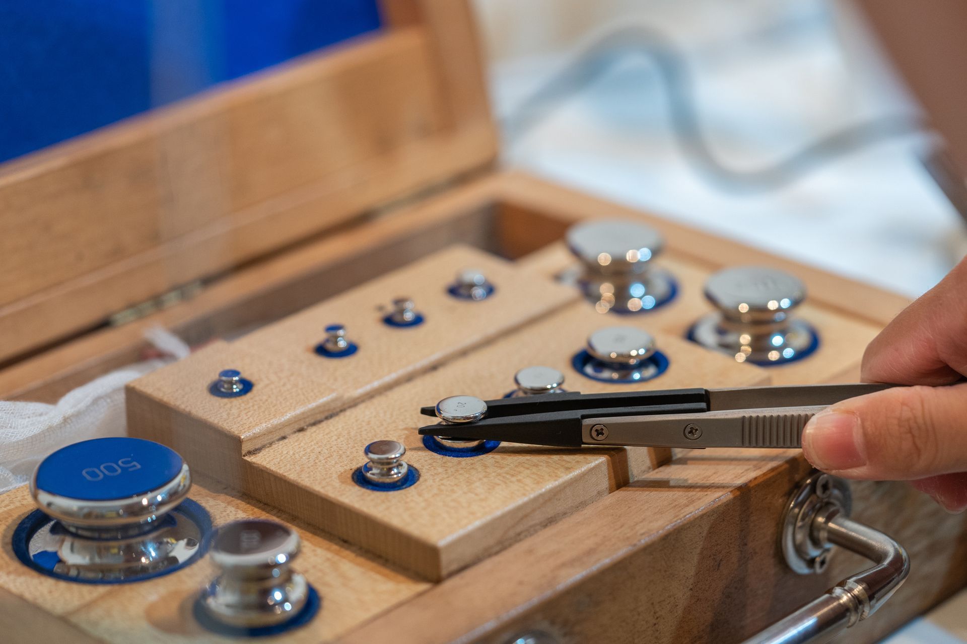 Calibration lab technician handling precision weights with tweezers. Calibration lab technician handling precision weights with tweezers.