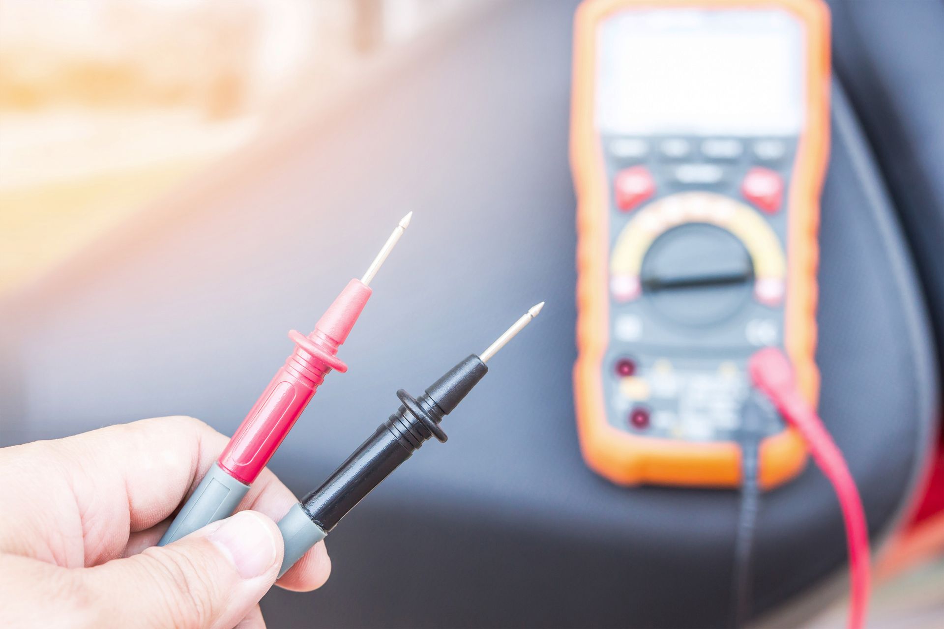 A Person Is Holding Two Test Probes in Their Hand in Front of A Multimeter. A Person Is Holding Two Test Probes in Their Hand in Front of A Multimeter.
