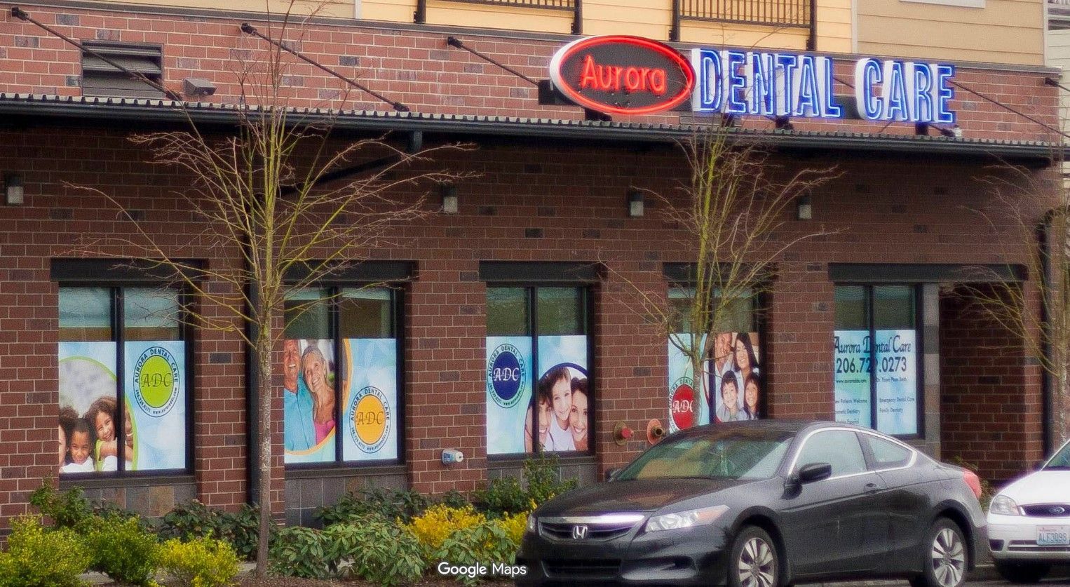 Exterior of Aurora Dental Care storefront with brick facade and parked cars in front