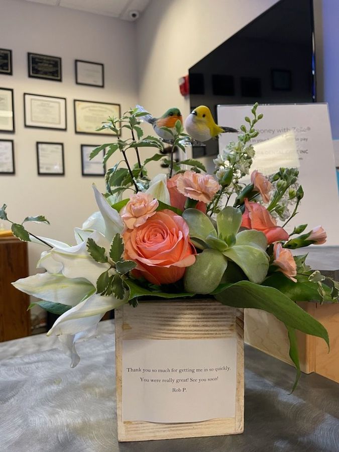 Floral bouquet with peach and white roses in a white vase on a table in an office lobby