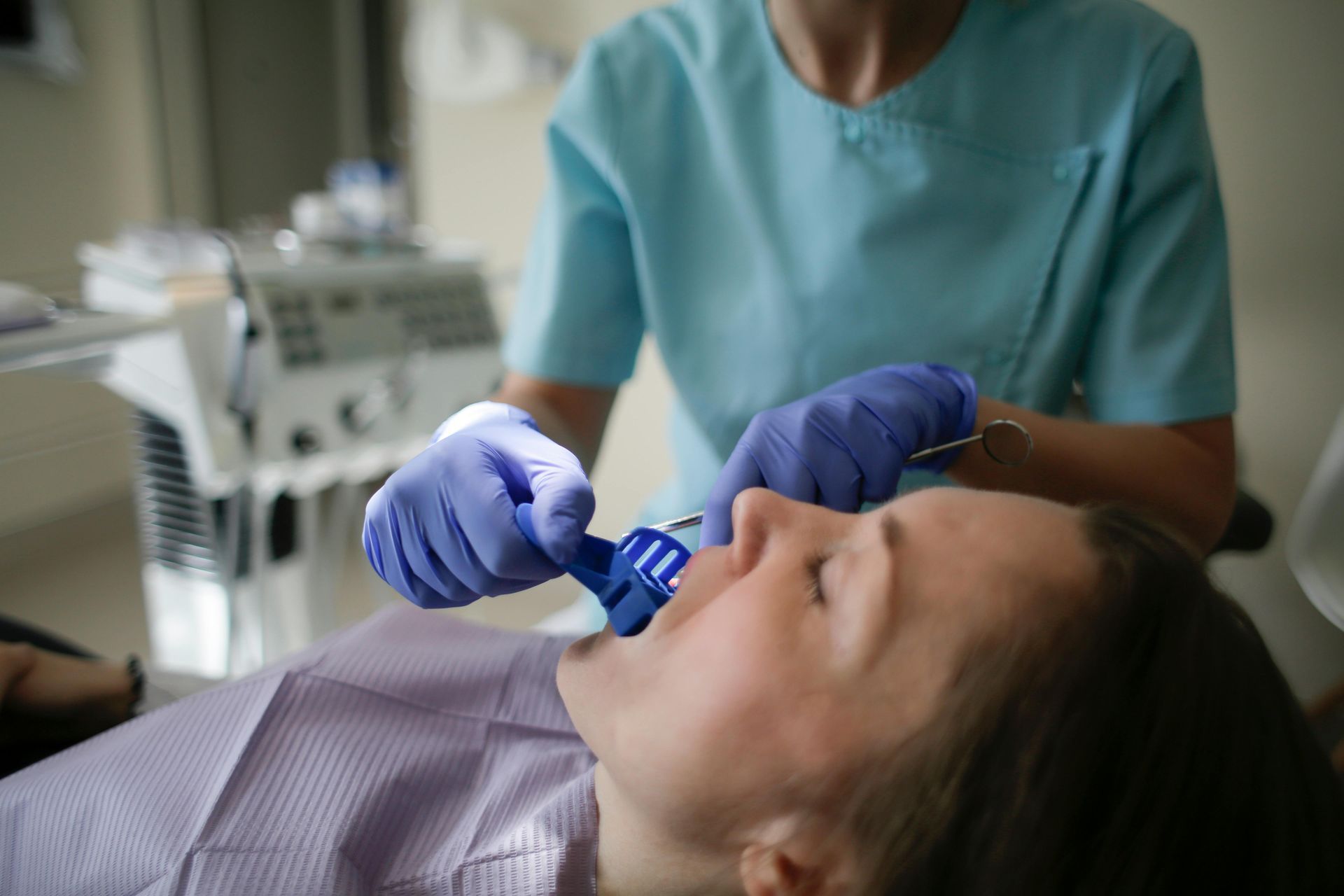 Dental professional examining a patient’s mouth with gloved hands in a clinic