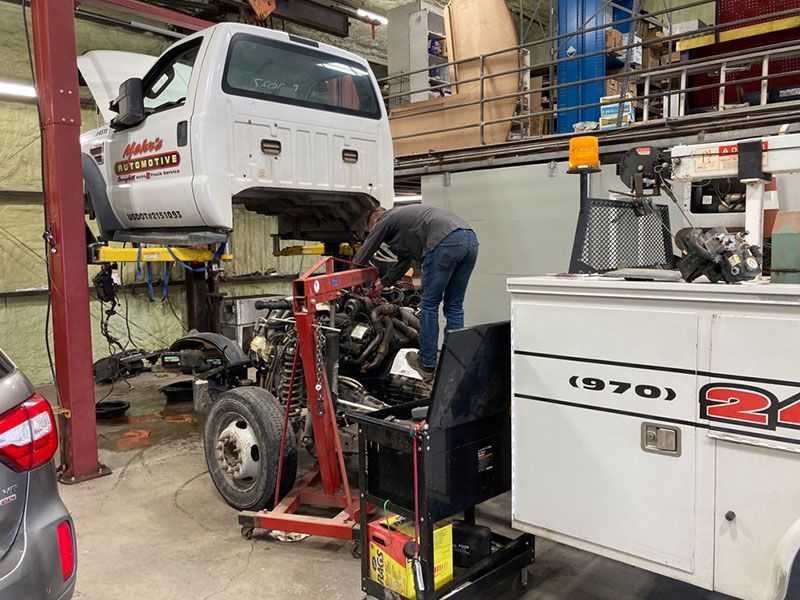 Expert technician working on a truck car engine in a garage. The truck is elevated. A cabinet is on the right. | Mohr's Automotive