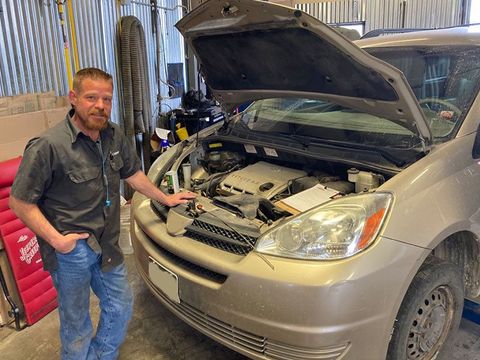 Mechanic technician standing next to a car with an open hood in a garage at Mohr's Automotive | Mohr's Automotive