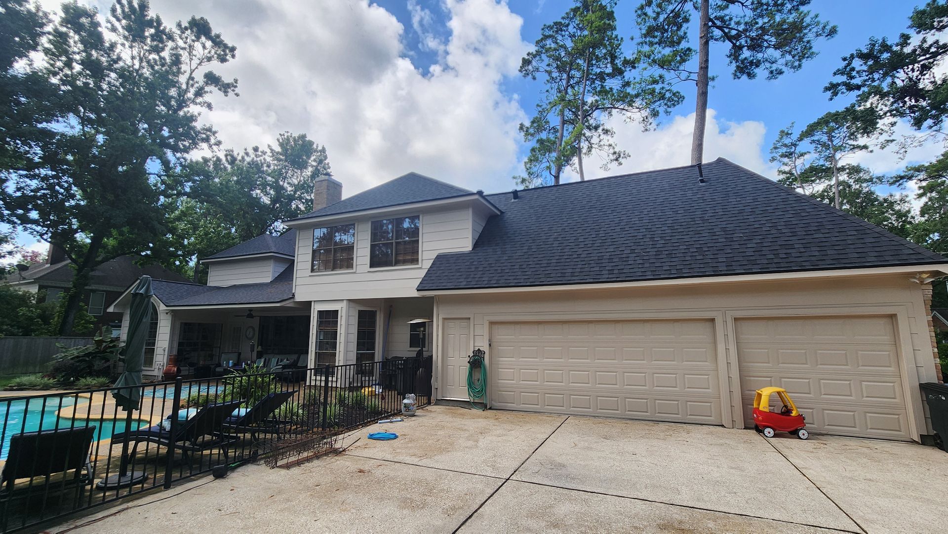 Two-story suburban house with white siding, dark roof, and two-car garage under a blue sky