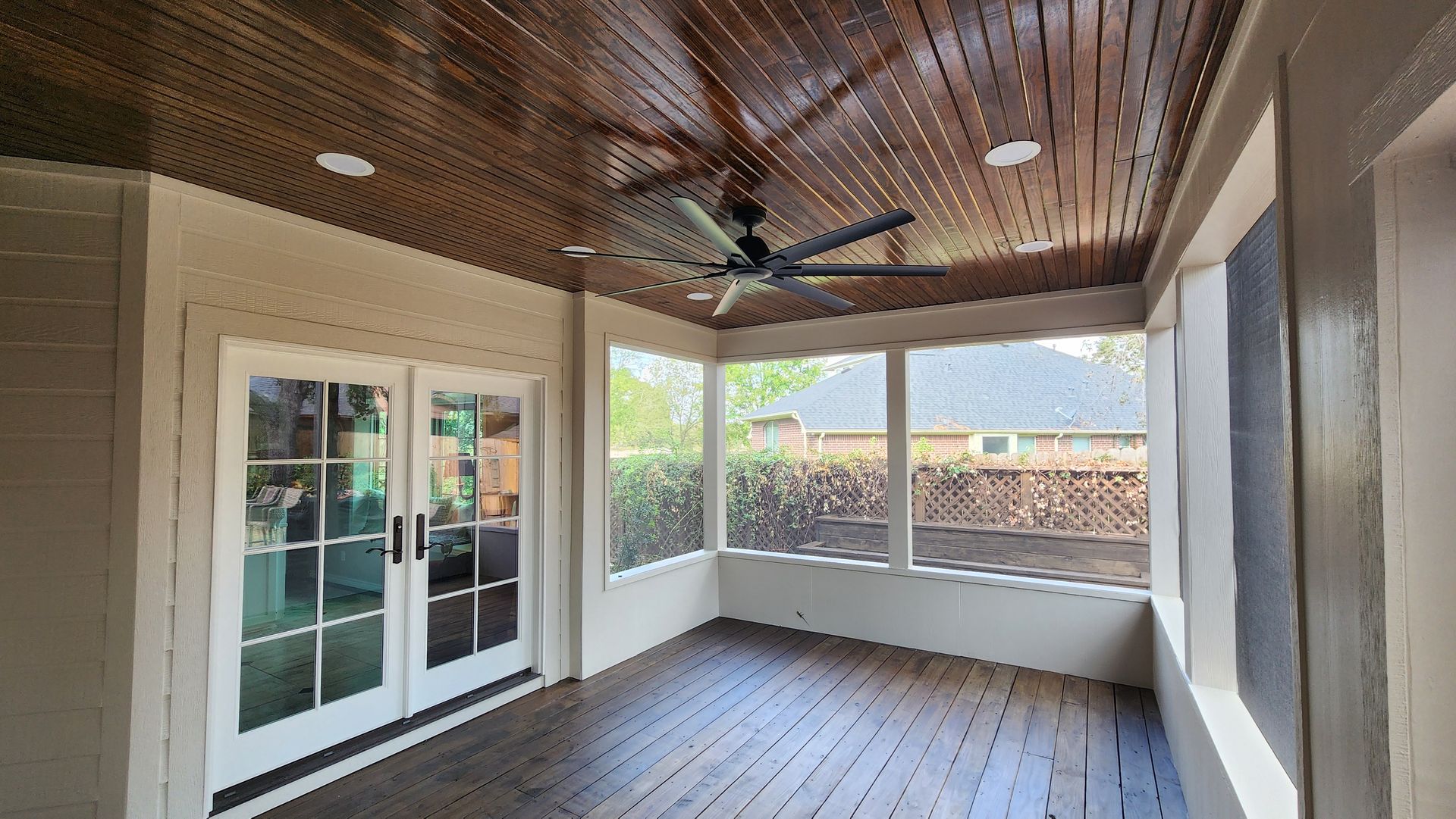Covered patio with wood ceiling, ceiling fan, French doors, and outdoor brick wall view