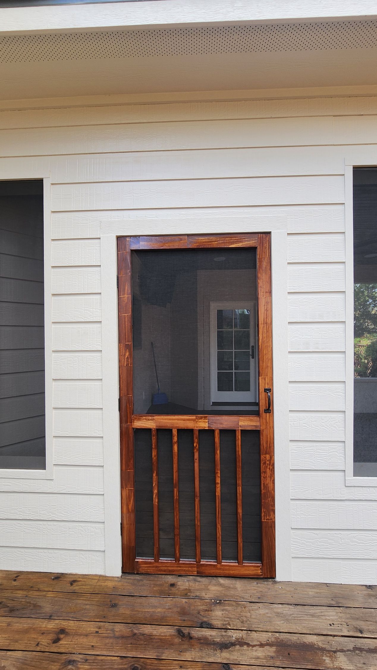 White house exterior with a small wooden screened door and brick walkway.