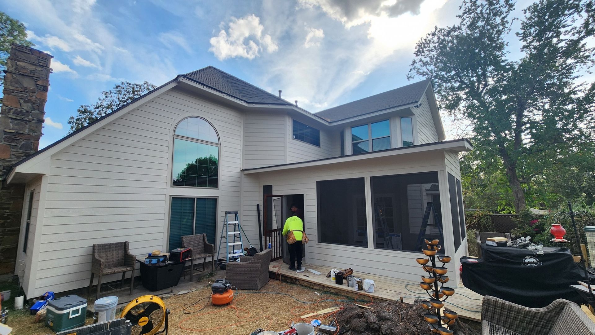 Two-story house under renovation with workers and construction tools in the front yard