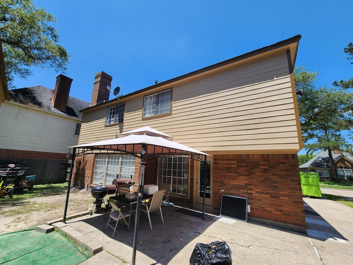 Backyard patio with umbrella-covered table beside a two-story brick and siding house