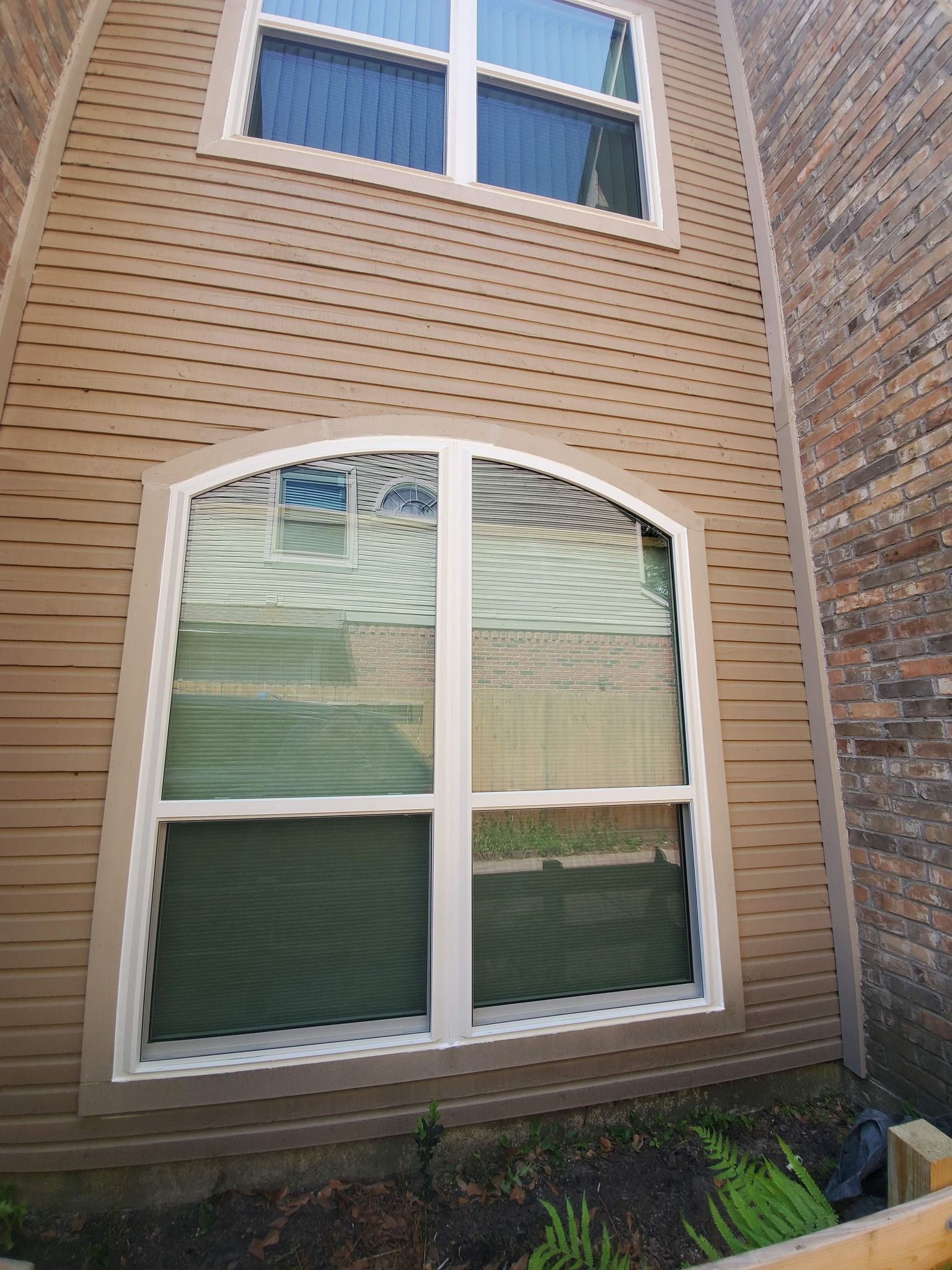 Brick house exterior with arched ground-floor window and smaller window above