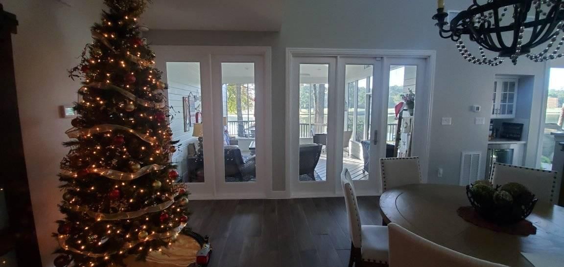 Living room with lit Christmas tree, white French doors, and a chandelier.