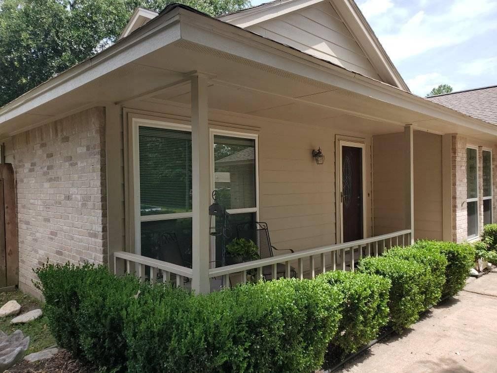 Single-story beige house with a front porch, white trim, and neatly trimmed shrubs.