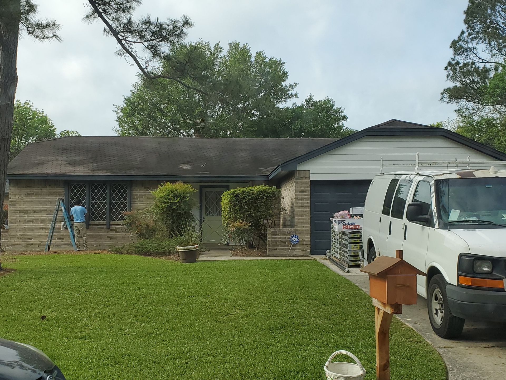 Single-story house with green lawn, white van, garage, and basketball hoop in the driveway.