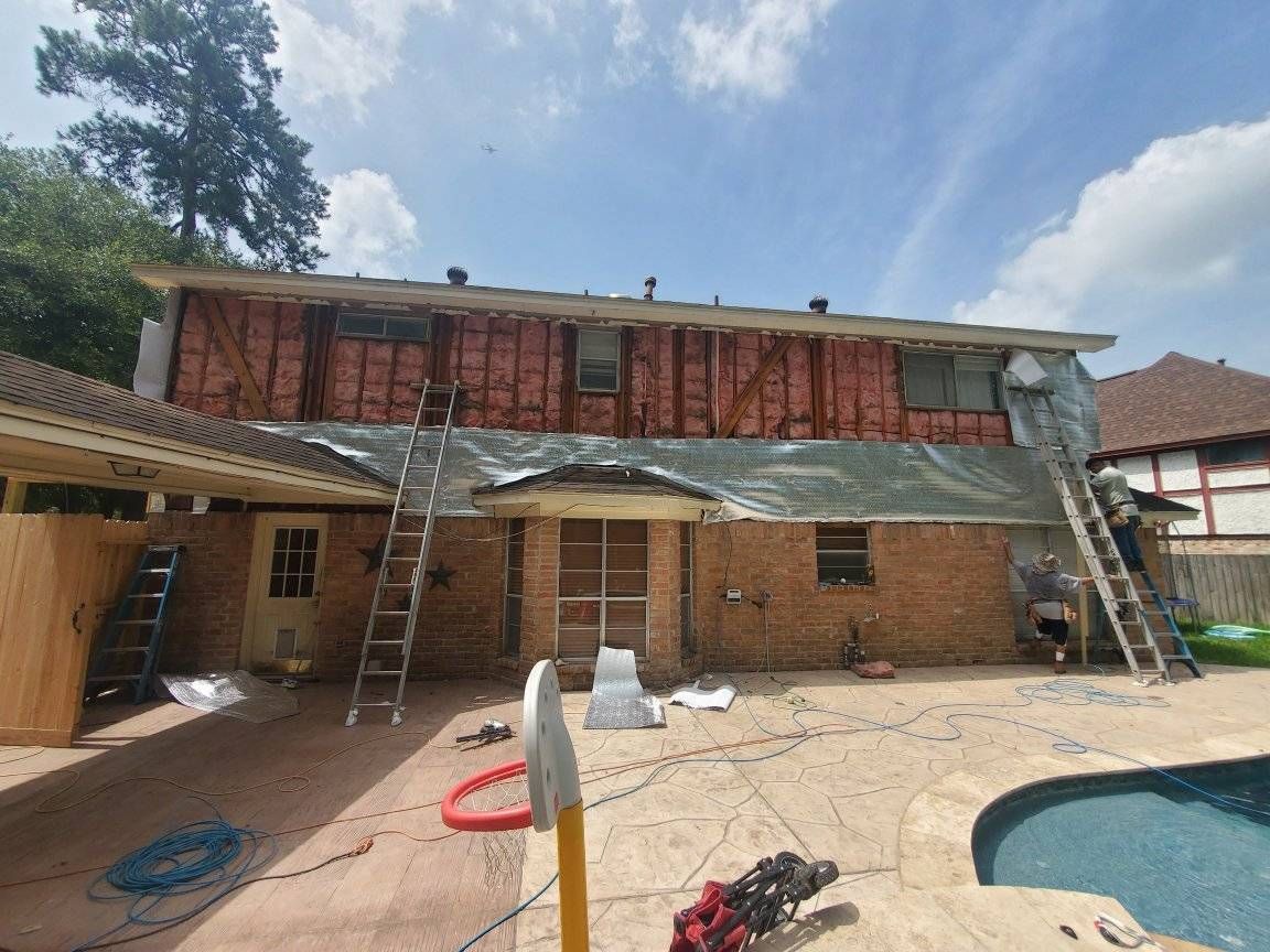 Backyard pool with a house under renovation, ladders leaning against the second story and roof under repair