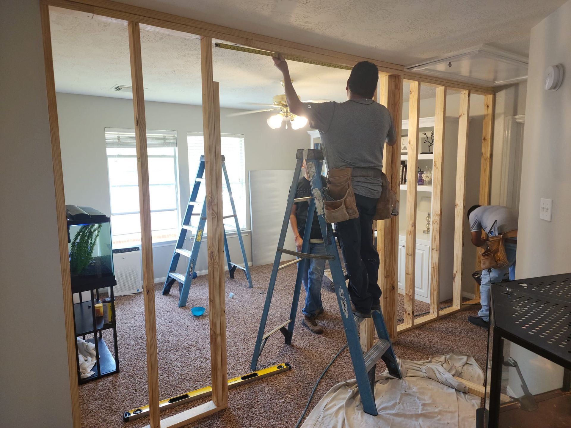 Two workers framing a wall during home renovation inside a living room