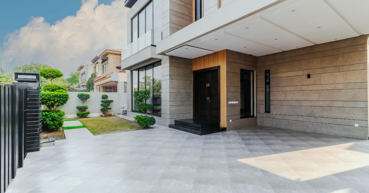 Modern apartment building entrance with a paved driveway and small landscaped garden