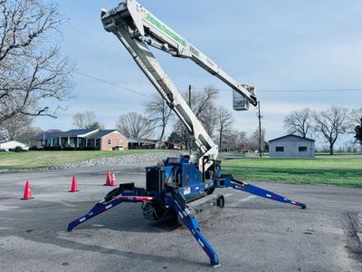 White utility truck with a boom lift parked on grass near industrial buildings.