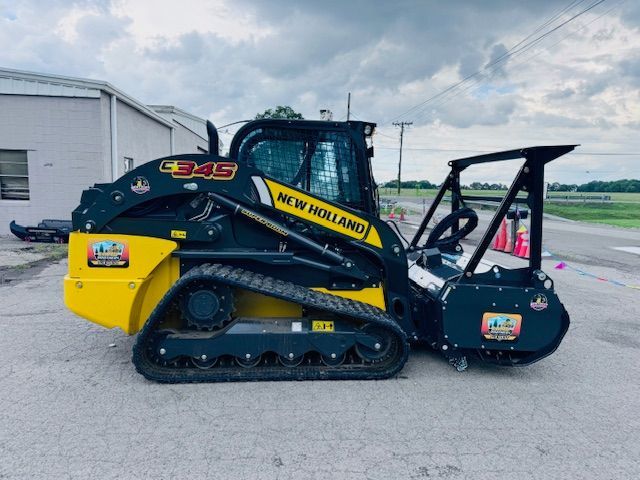 A yellow and black new holland tractor is parked in front of a building.