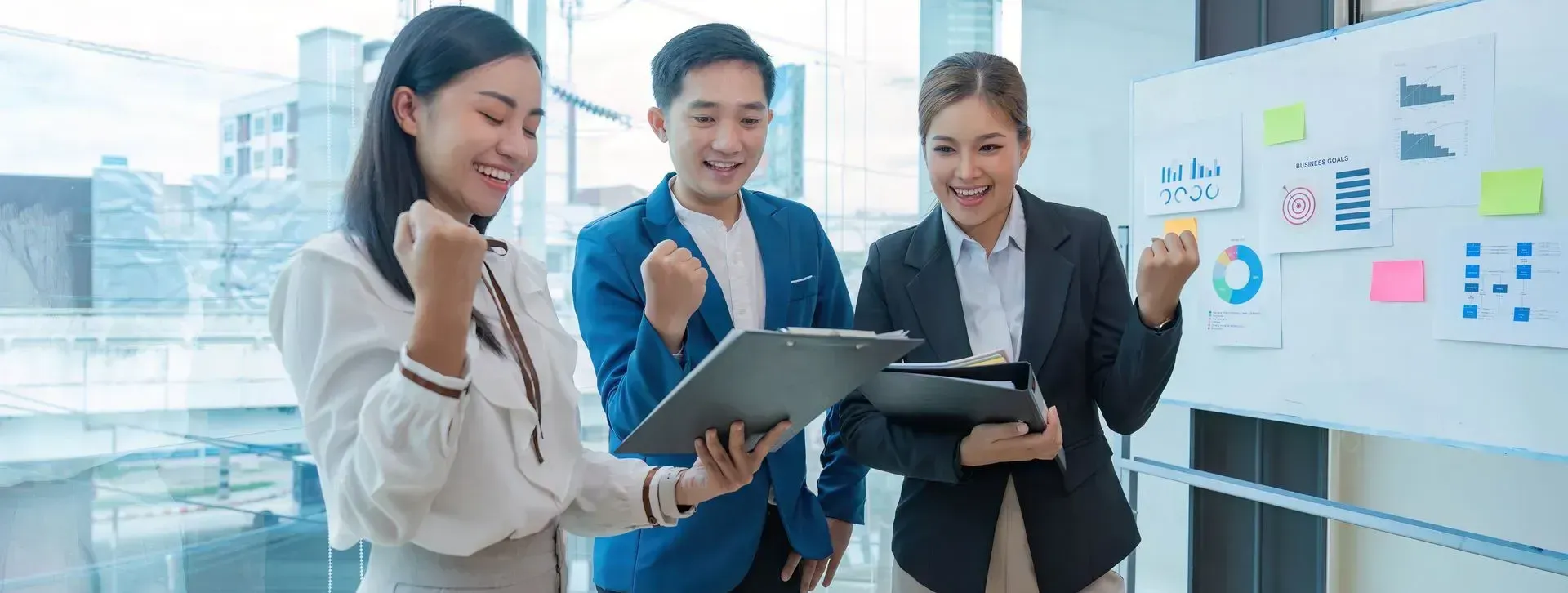 A group of business people are standing in front of a whiteboard.