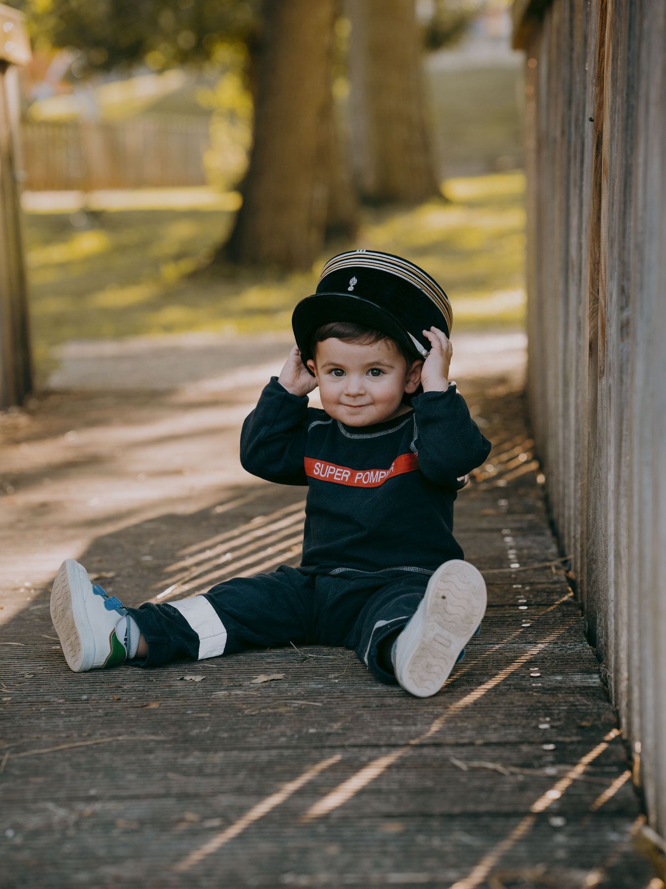 Un petit garçon est assis par terre avec un chapeau.