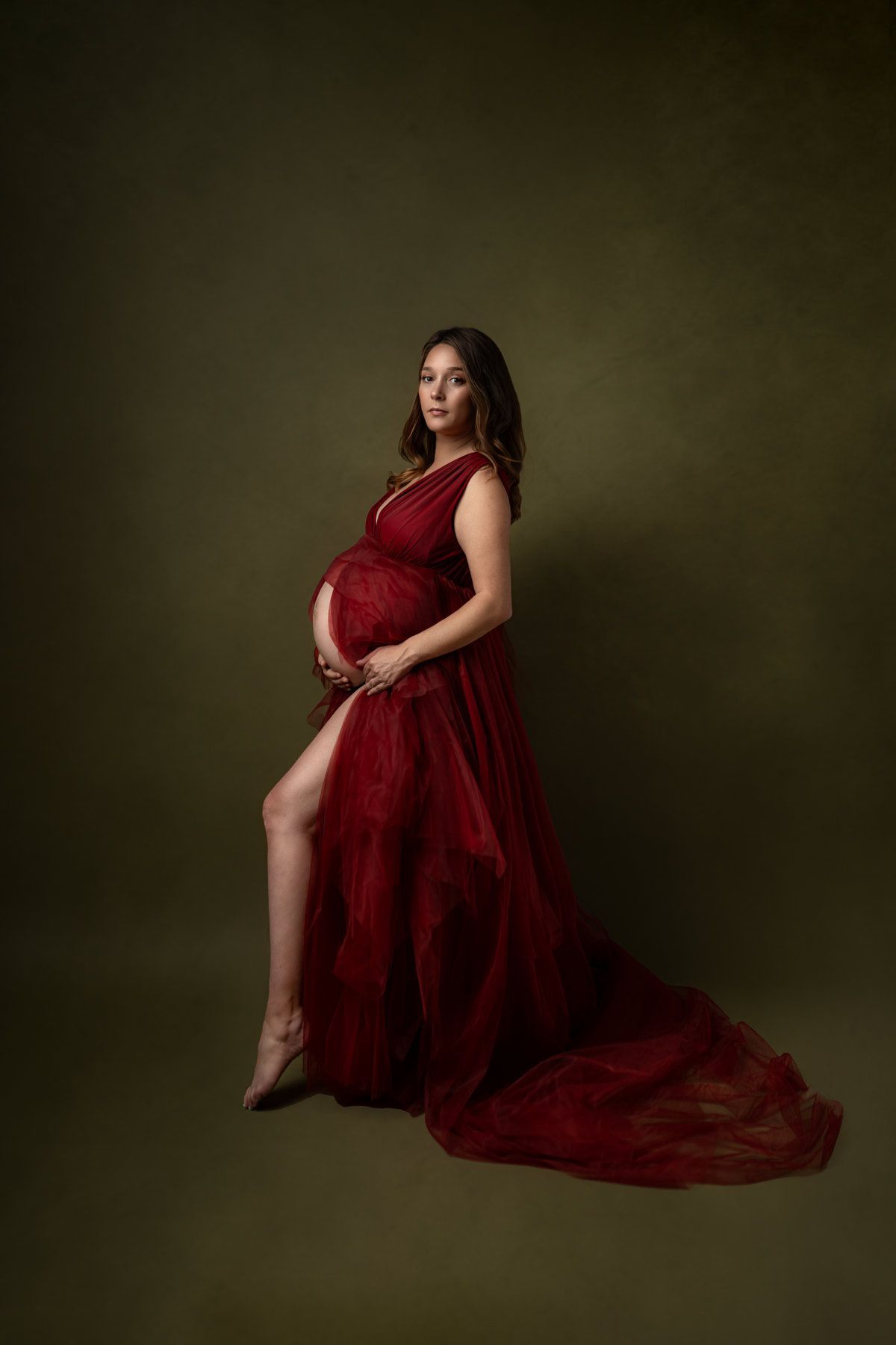 Une femme enceinte est habillée en ange avec des ailes blanches.