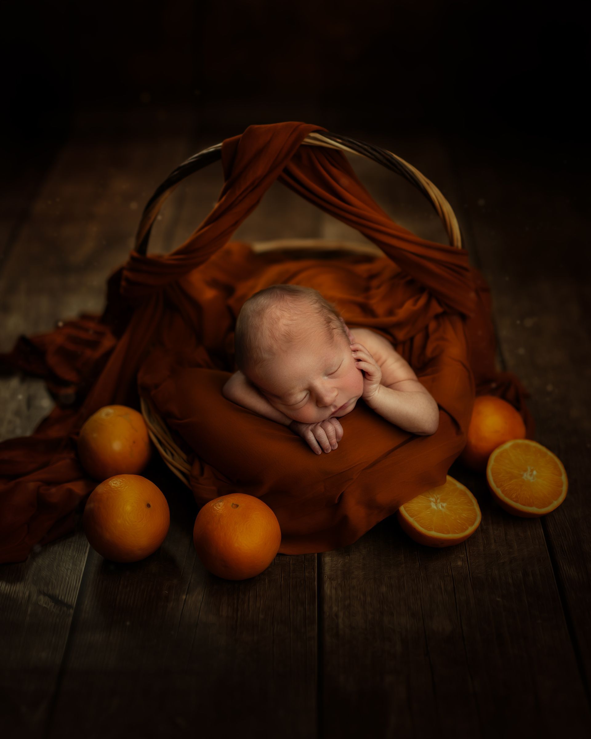 Un nouveau-né dort dans un panier en osier sur un plancher en bois.
