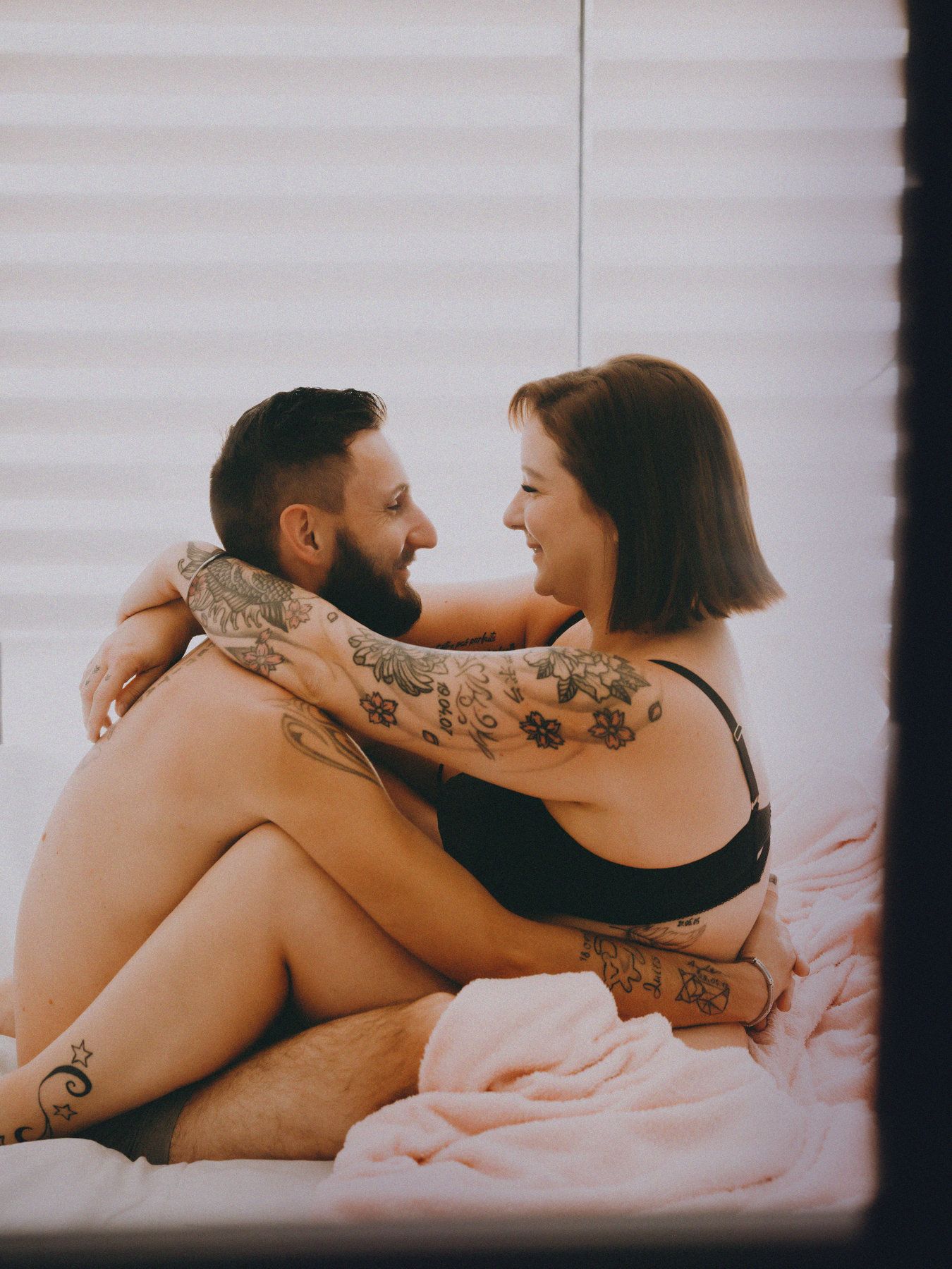 Un homme et une femme se serrent dans les bras sur un lit.