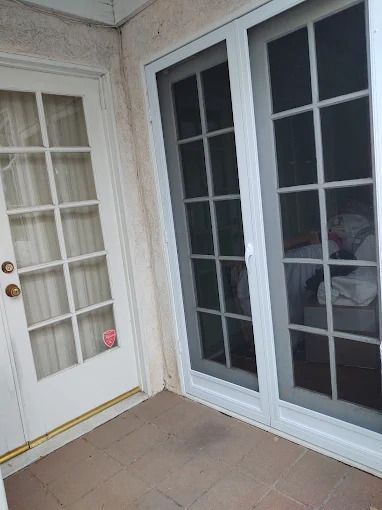 Patio corner with white French doors, glass panels, and tan tile floor.