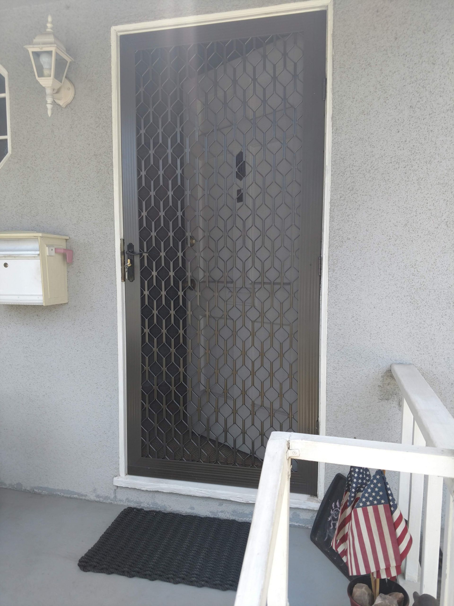 Front porch with a black security door, white mailbox, and American flag decoration near the entrance