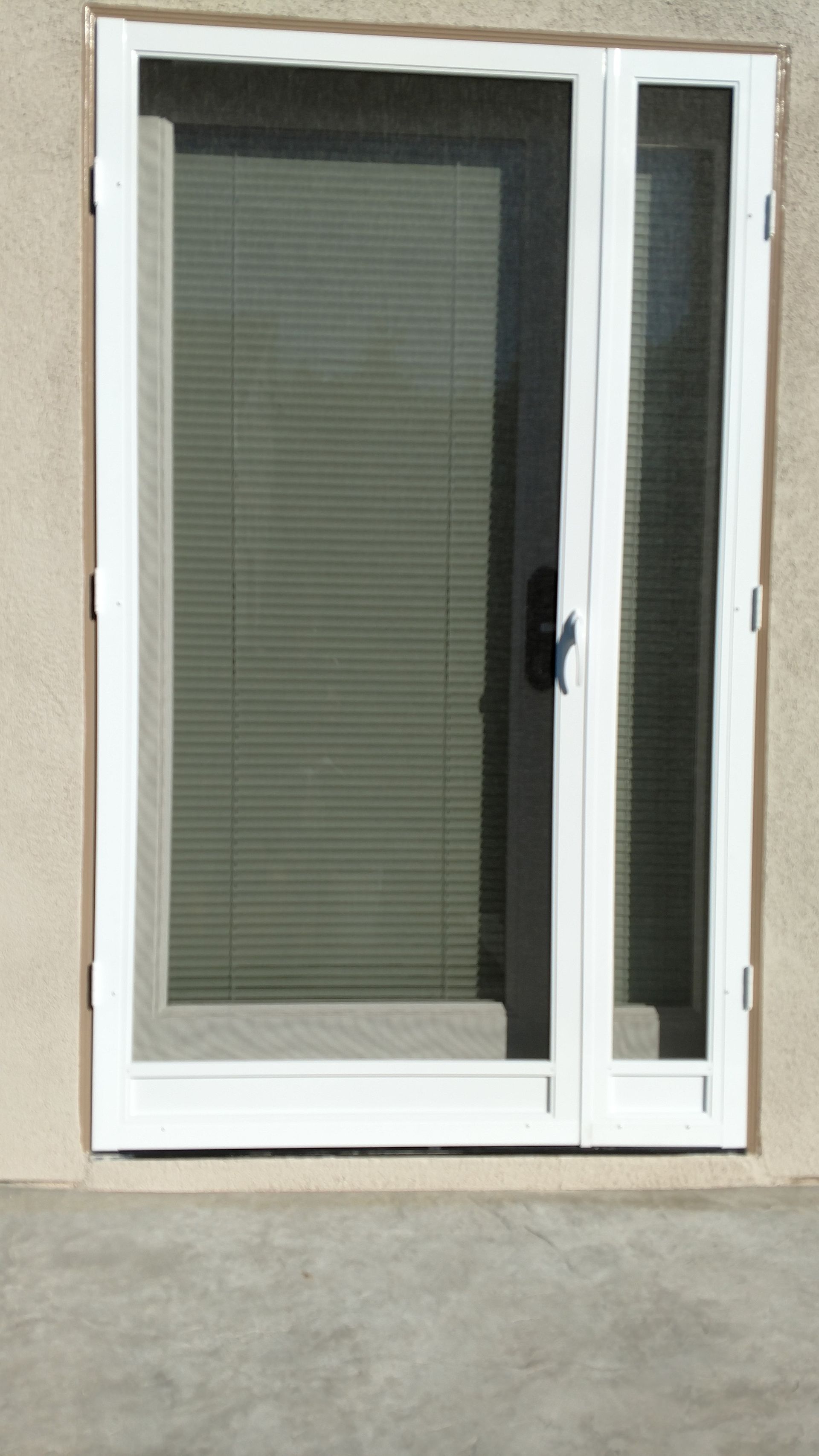 White sliding glass patio door with blinds, set in a beige exterior wall.