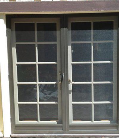 White-framed French doors with glass panes and a brown awning above.