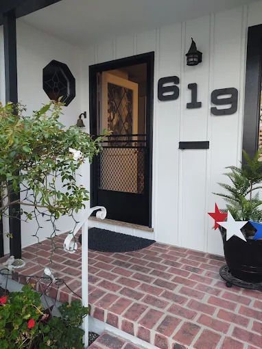 Front porch with brick steps, black door, white siding, and house number 619.