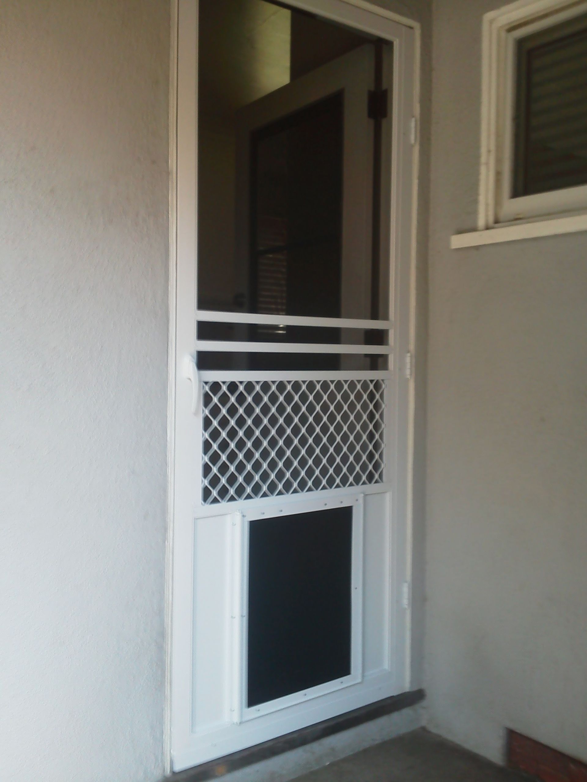 White security screen door in a beige wall opening onto a dim interior entryway.