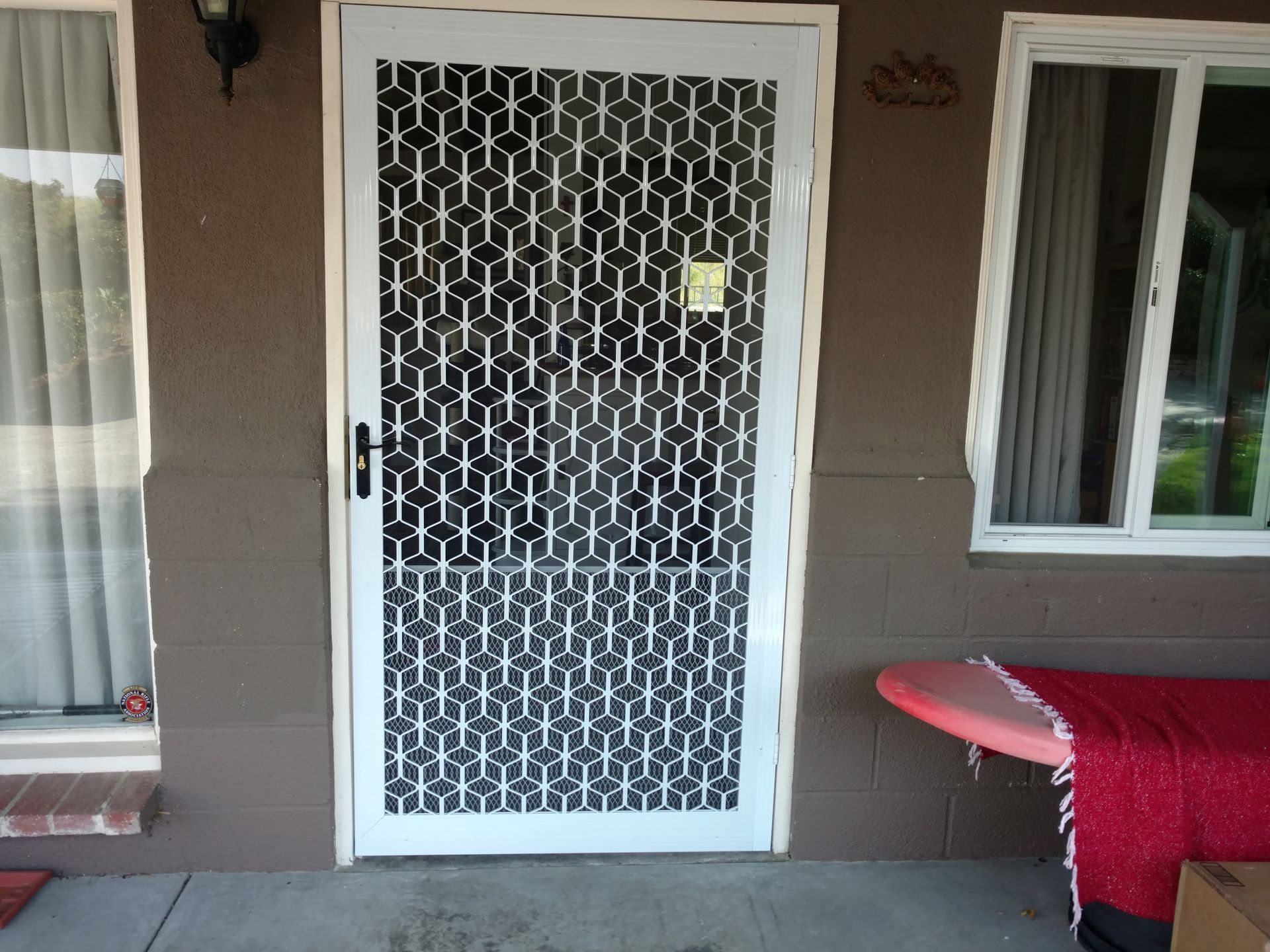 Front porch with a white security door, window, and red-covered table on the right