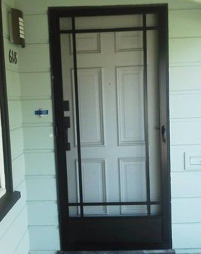 Black metal security door on a house porch, with white front door behind it.