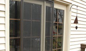 Sliding glass doors beside a beige house wall, with a small hanging wind chime outside