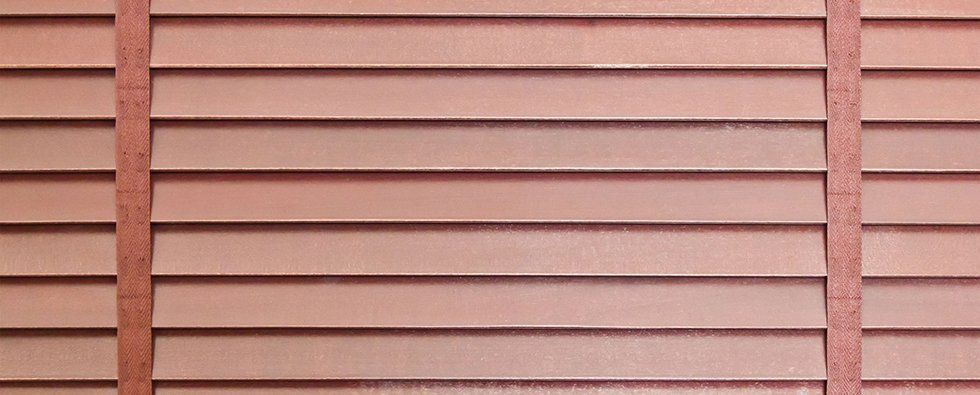 Pink horizontal house siding with red trim and a central vertical support.