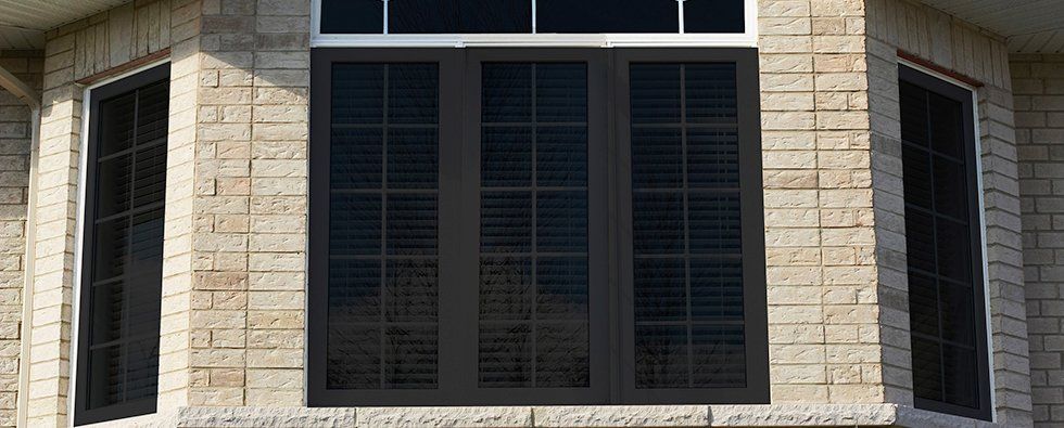 Stone building facade with dark barred windows and a central black-framed window