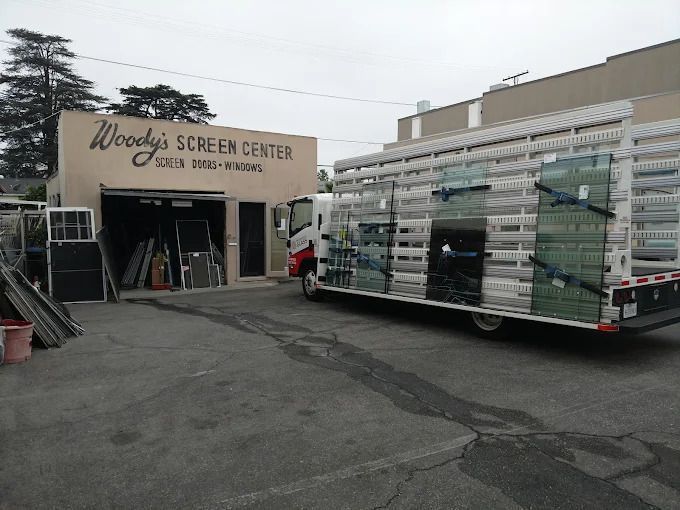 Trailer loaded with stacked glass panels outside Woody Screen Center storefront
